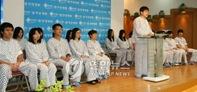会見を行う21人の帰国者。中央は代表に立ったユ・ギョンシクさん＝12日、安養（聯合）