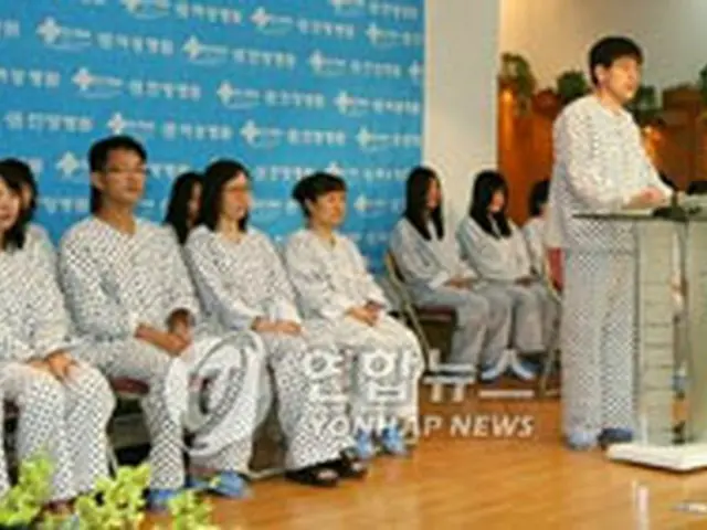 会見を行う21人の帰国者。中央は代表に立ったユ・ギョンシクさん＝12日、安養（聯合）
