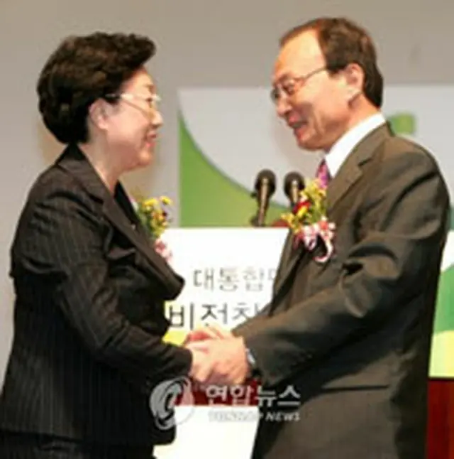 手を取り合う韓明淑氏（左）と李海チャン氏＝14日、ソウル（聯合）