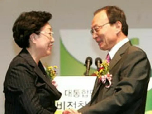 手を取り合う韓明淑氏（左）と李海チャン氏＝14日、ソウル（聯合）