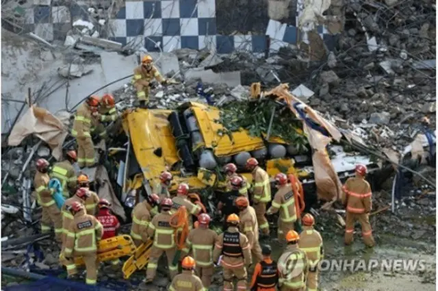 がれきの下敷きになったバス。救急隊員が救助作業を行っている＝９日、光州（聯合ニュース）