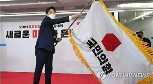 党代表に選出後、党旗を振る李氏＝１１日、ソウル（聯合ニュース）