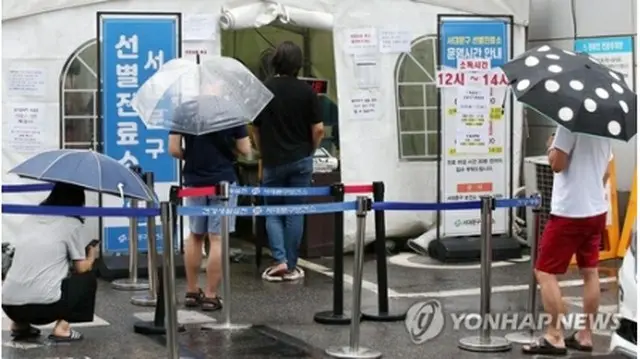 １日、雨の中、新型コロナウイルスの検査を受ける人たち＝（聯合ニュース）