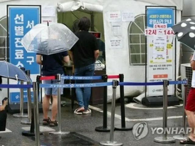 １日、雨の中、新型コロナウイルスの検査を受ける人たち＝（聯合ニュース）