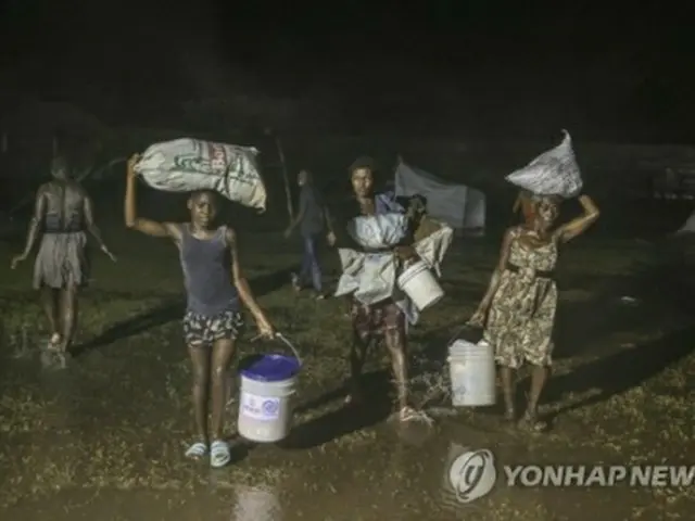 雨の中、難民キャンプを歩くハイチの人々＝（AP＝聯合ニュース）