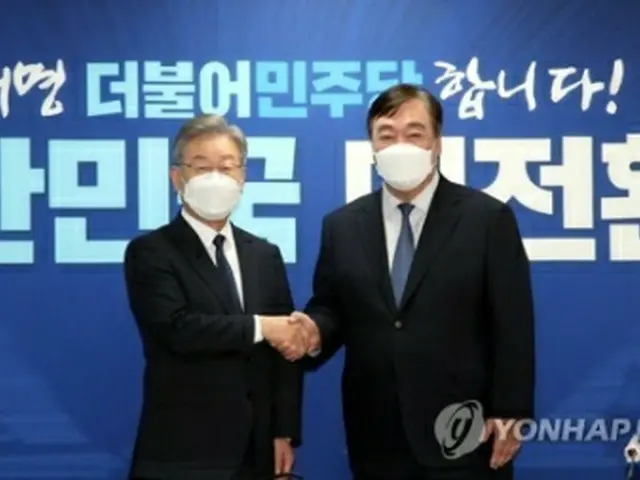 ソウル市内の共に民主党の党本部で握手を交わす李在明氏（左）とケイ海明氏（国会写真記者団）＝１１日、ソウル（聯合ニュース）≪転載・転用禁止≫