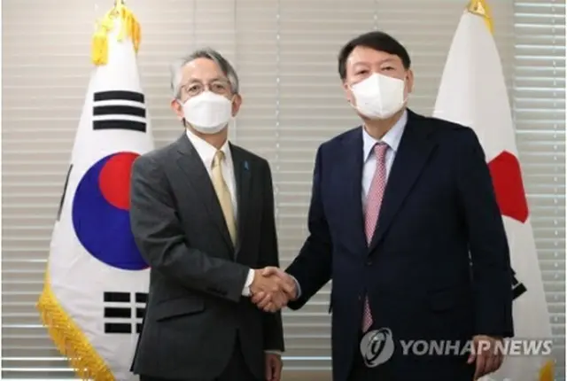 握手を交わす尹氏（右）と相星氏（国会写真記者団）＝２６日、ソウル（聯合ニュース）