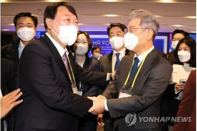 11月10日、ソウル市内のホテルで開かれたフォーラムで握手を交わす尹錫悦氏（左）と李在明氏（国会写真記者団）＝（聯合ニュース）