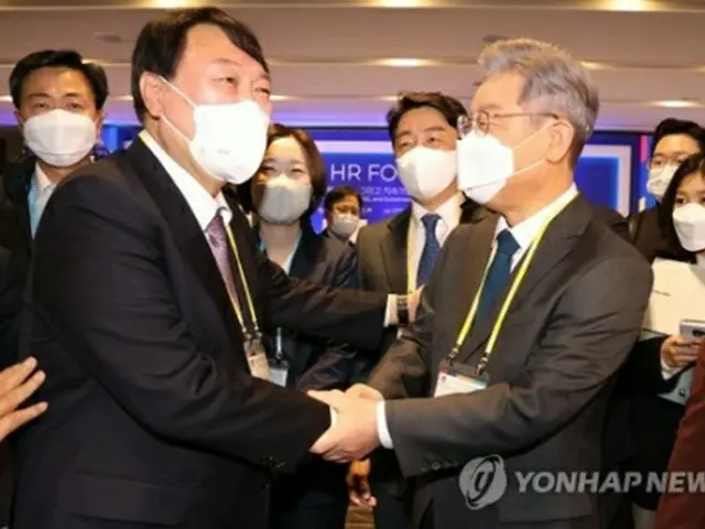11月10日、ソウル市内のホテルで開かれたフォーラムで握手を交わす尹錫悦氏（左）と李在明氏（国会写真記者団）＝（聯合ニュース）