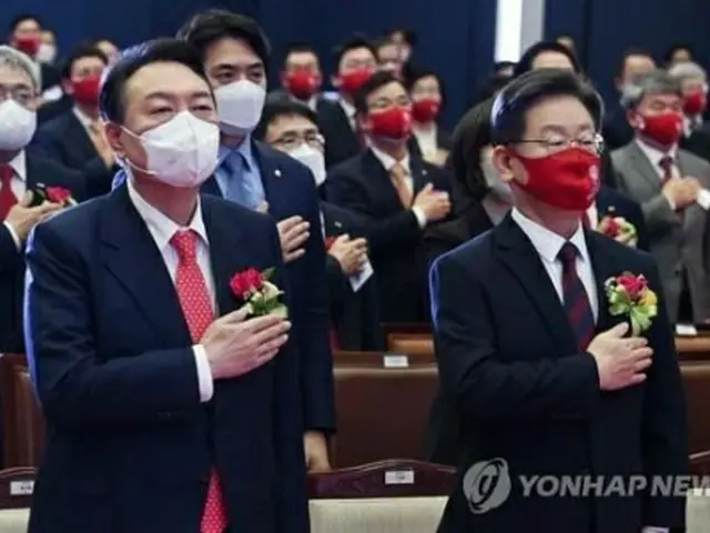 韓国取引所で１年の株式取引の始まりを告げる開場式（大発会に相当）が開かれ、李氏（前列右）と尹氏（同左）が出席した。国旗に敬礼する両氏（国会写真記者団）＝３日、ソウル（聯合ニュース）