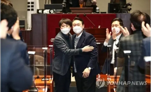 議員総会で和解した李氏（左）と尹氏（国会写真記者団）＝６日、ソウル（聯合ニュース）