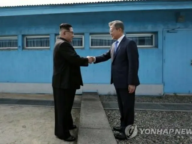 18年4月27日、軍事境界線を挟んで握手を交わす文大統領(右)と金正恩氏=(聯合ニュース)