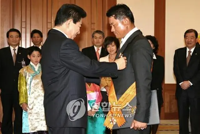 盧武鉉大統領から体育勲章を授与されるチェ・ギョンジュ選手＝23日、ソウル（聯合）