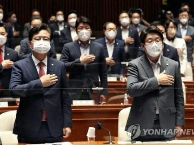 国旗に敬礼する権性東氏（右、国会写真記者団）＝１１日、ソウル（聯合ニュース）
