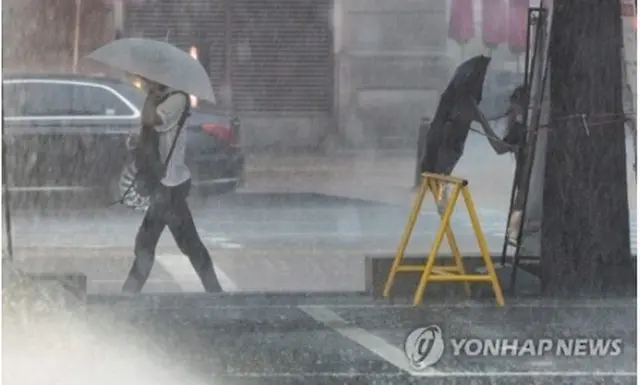 大雨の中を帰宅する人たち＝８日、ソウル（聯合ニュース）