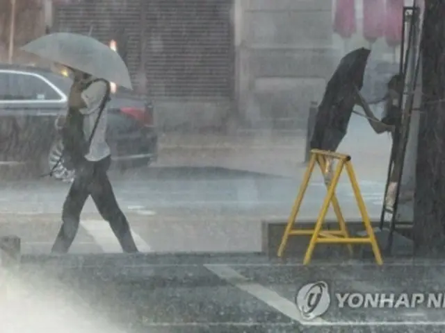 大雨の中を帰宅する人たち＝８日、ソウル（聯合ニュース）