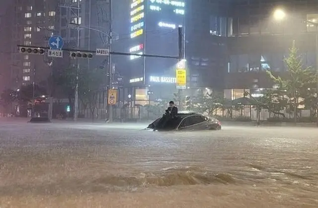 8日、ソウル市ソチョドン（瑞草洞）で浸水した車の上に登っている男性（画像提供:wowkorea）
