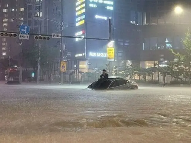 8日、ソウル市ソチョドン（瑞草洞）で浸水した車の上に登っている男性（画像提供:wowkorea）