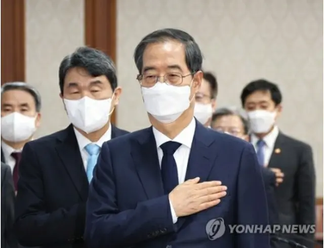 閣議で国旗に敬礼する韓国の韓首相＝8日、ソウル（聯合ニュース）