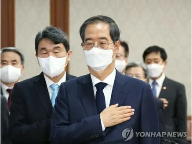 閣議で国旗に敬礼する韓国の韓首相＝8日、ソウル（聯合ニュース）