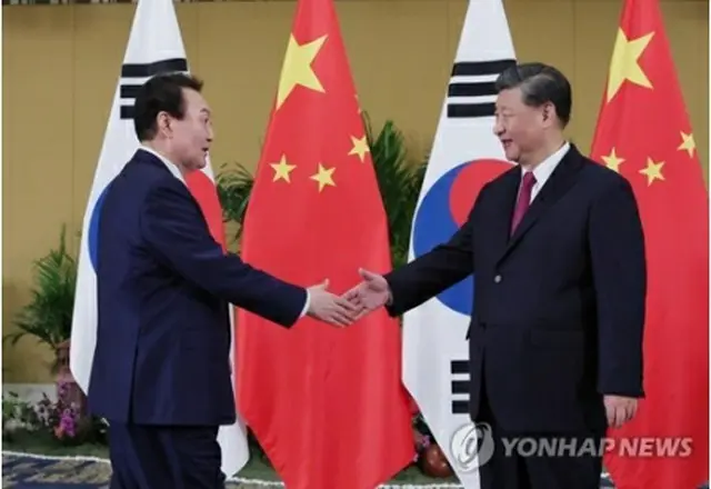 握手を交わす尹大統領（左）と習主席＝１５日、バリ島（聯合ニュース）