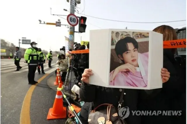 ＪＩＮさんの写真を掲げるファン＝１３日、漣川（聯合ニュース）
