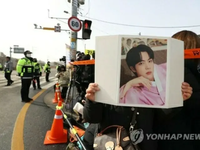 ＪＩＮさんの写真を掲げるファン＝１３日、漣川（聯合ニュース）