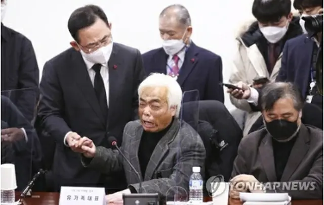 遺族と握手する朱氏（左・共同取材）＝２０日、ソウル（聯合ニュース）