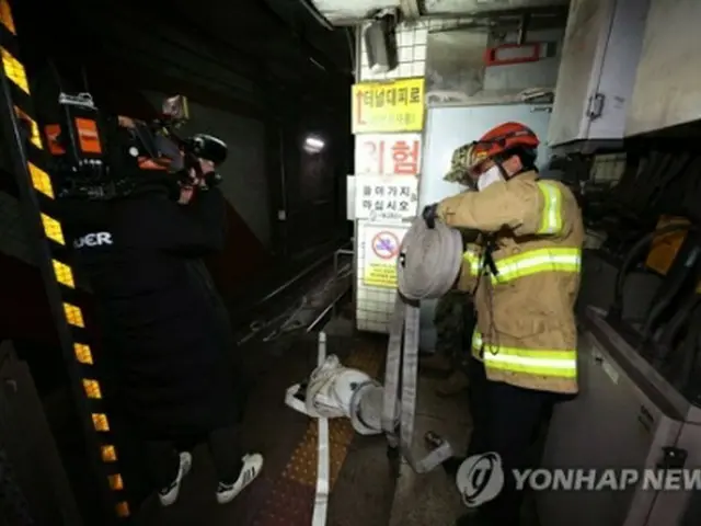 独立門駅で消火作業に当たる消防隊員＝23日、ソウル（聯合ニュース）