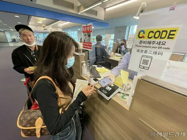 韓国仁川空港入国場の検疫台で、外国人旅行客がQ-CODE（検疫事前情報システム）を提出している様子（画像提供:wowkorea）