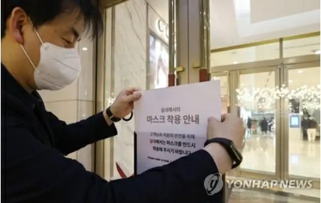 韓国で３０日から公共交通機関などを除いて屋内でのマスク着用義務が解除される。２９日午後、ソウル市内の百貨店でマスク着用を呼びかける貼り紙を撤去する関係者＝（聯合ニュース）
