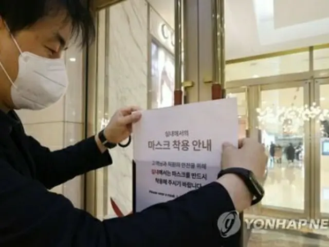 韓国で３０日から公共交通機関などを除いて屋内でのマスク着用義務が解除される。２９日午後、ソウル市内の百貨店でマスク着用を呼びかける貼り紙を撤去する関係者＝（聯合ニュース）