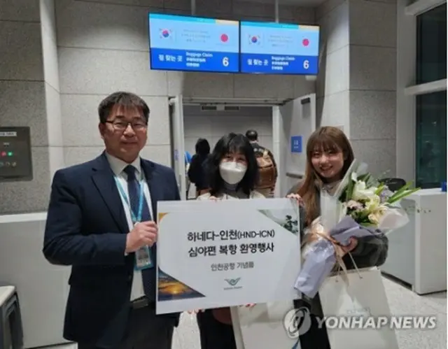 27日未明、仁川国際空港に到着した日本人の女性たち。仁川国際空港公社の担当者から記念品を贈られた（同公社提供）＝（聯合ニュース）≪転載・転用禁止≫