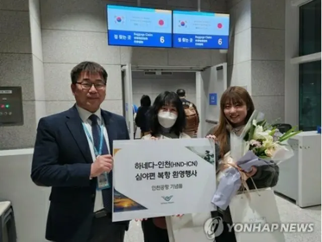 27日未明、仁川国際空港に到着した日本人の女性たち。仁川国際空港公社の担当者から記念品を贈られた（同公社提供）＝（聯合ニュース）≪転載・転用禁止≫