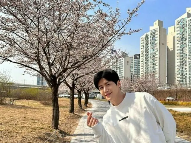 俳優キム・ソンホ、桜の木の前で指ハート…春のように明るいえくぼスマイルで癒しオーラ発散（画像提供:wowkorea）