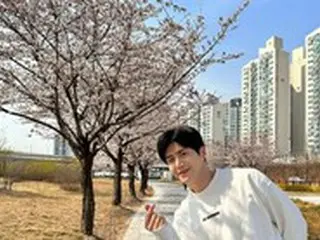 俳優キム・ソンホ、桜の木の前で指ハート…春のように明るいえくぼスマイルで癒しオーラ発散