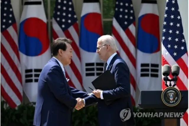 首脳会談後に開いた共同記者会見で握手を交わす尹大統領（左）とバイデン大統領＝26日、ワシントン（聯合ニュース）