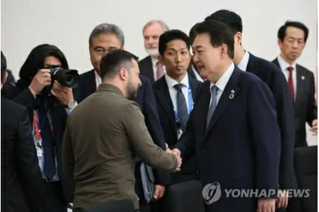 拡大会議で握手を交わす韓国の尹大統領（右）とウクライナのゼレンスキー大統領（共同取材）＝２１日、広島（聯合ニュース）