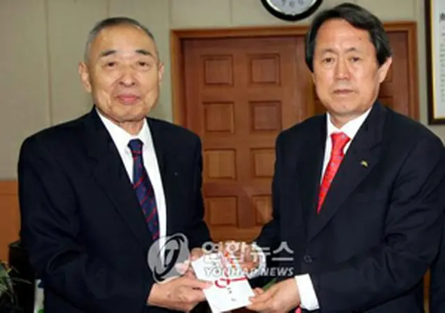 済州道の金泰煥知事に寄付金を手渡す向井さん（左）＝23日、済州（聯合）