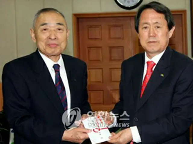 済州道の金泰煥知事に寄付金を手渡す向井さん（左）＝23日、済州（聯合）