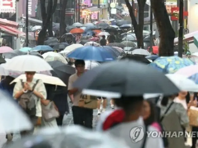 今月１１日、ソウルの繁華街・明洞で傘を差して歩く人々＝（聯合ニュース）