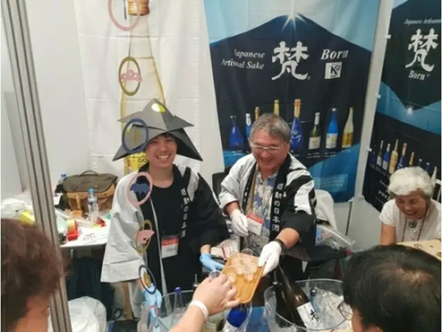 来場客に酒を振る舞うイベント関係者＝２９日、ソウル（聯合ニュース）