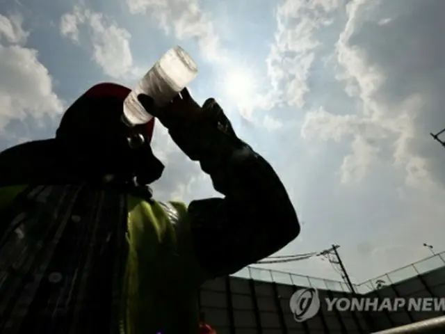 ソウル市内の工事現場で働く作業員が水を飲んでいる。ソウルでは１日、日中の最高温度が３５度を記録した＝１日、ソウル（聯合ニュース）