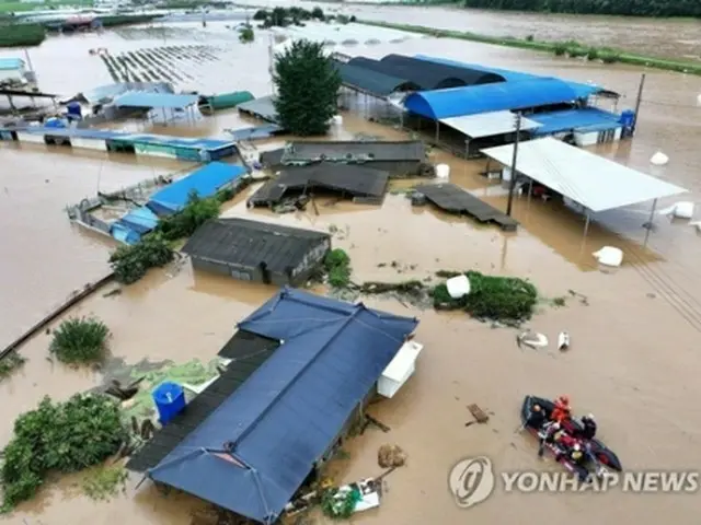 台風６号による大雨で韓国南東部・大邱市軍威郡を流れる川の堤防が決壊し、付近の集落が水にのまれた＝１０日、大邱（聯合ニュース）