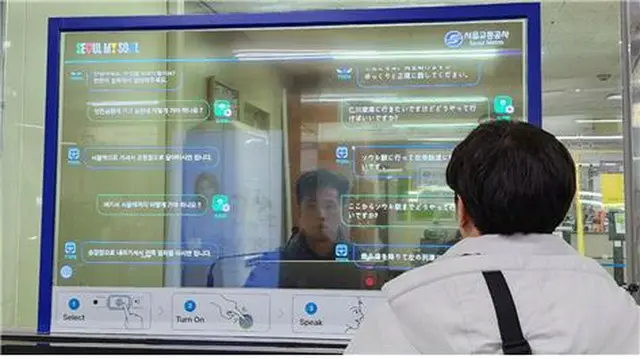透明有機ＥＬディスプレー越しに駅職員が外国人客に地下鉄利用を案内する（ソウル交通公社提供）＝（聯合ニュース）≪転載・転用禁止≫