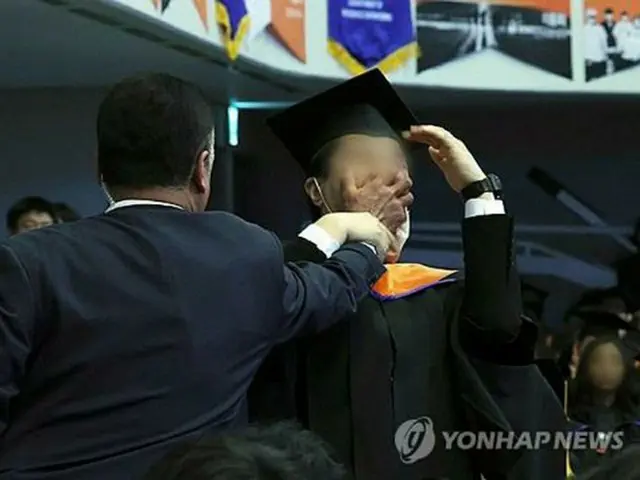 韓国科学技術院の学位授与式で警護員に口をふさがれる卒業生（大統領室通信写真記者団）＝１６日、ソウル（聯合ニュース）