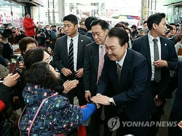 南部・慶尚南道昌原市の水産市場を訪問し、市民と握手する尹大統領＝２２日、昌原（聯合ニュース）