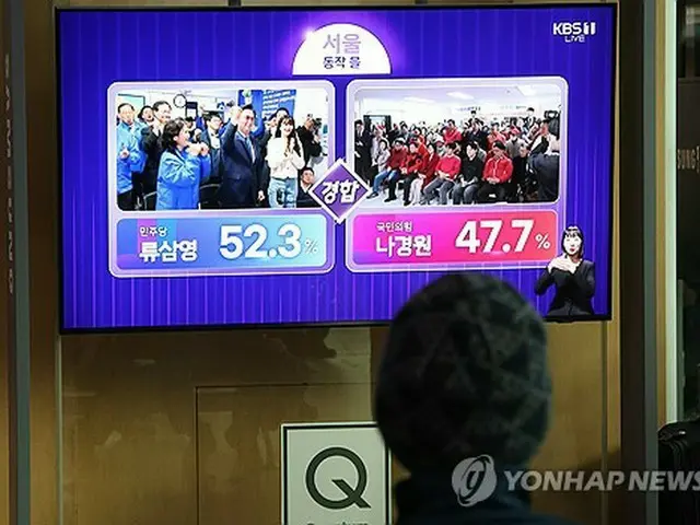 ソウル駅構内に設置されたテレビで、「共に民主党」の柳三栄（リュ・サムヨン）候補と「国民の力」の羅卿ウォン（ナ・ギョンウォン）候補が出馬した選挙区の出口調査の結果を視聴する市民ら＝１０日、ソウル（聯合ニュース）