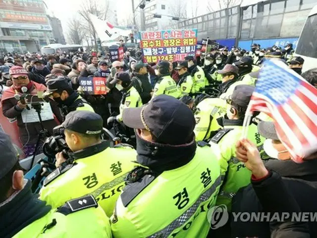 憲法裁判所の近くで対峙する警察とデモ隊＝２１日、ソウル（聯合ニュース）