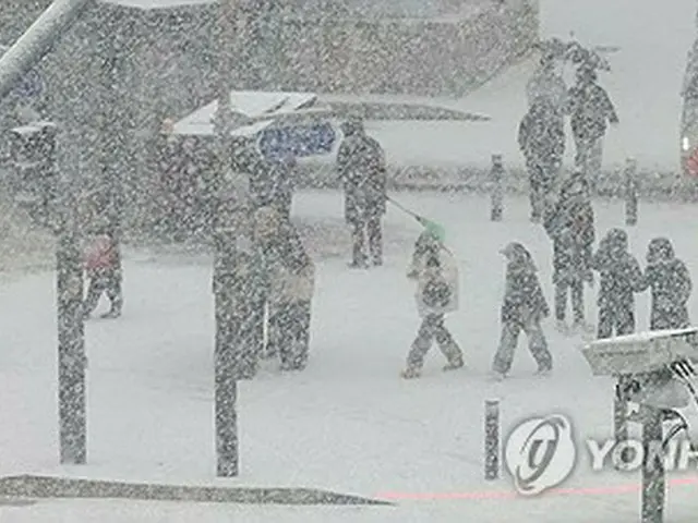 雪が降る中、ソウル市内を歩く市民ら＝６日、ソウル（聯合ニュース）